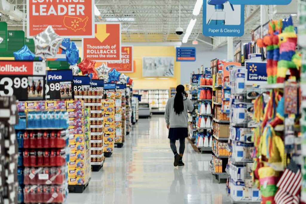 someone walking down the aisles in a supermarket, with aisles of cleaning products on the right and processed food to the left