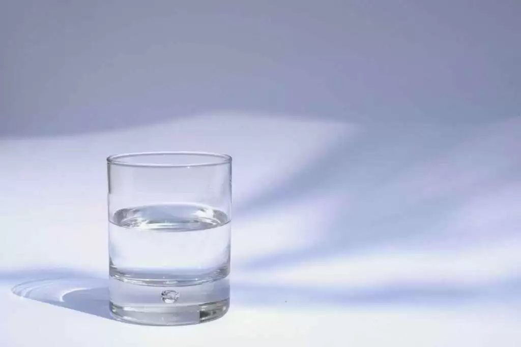 a glass of remineralized water with a plain gray white background